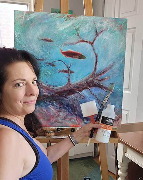 Canadian wildlife artist Pam Paulenko in front of her easel painting fish on Canvas