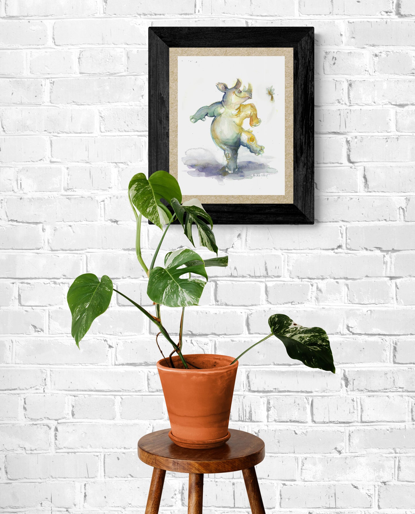 Here Pam's original artwork of a dancing rhinoceros can be seen framed above a potted plant 